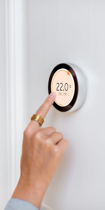 une main qui montre un thermostat à 22°